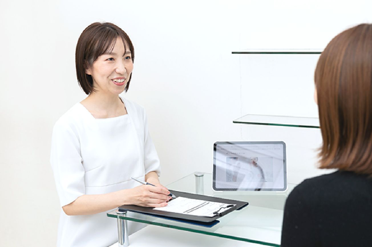 宮本さんがカルテにメモを取りながらお客さまのカウンセリングをする様子。