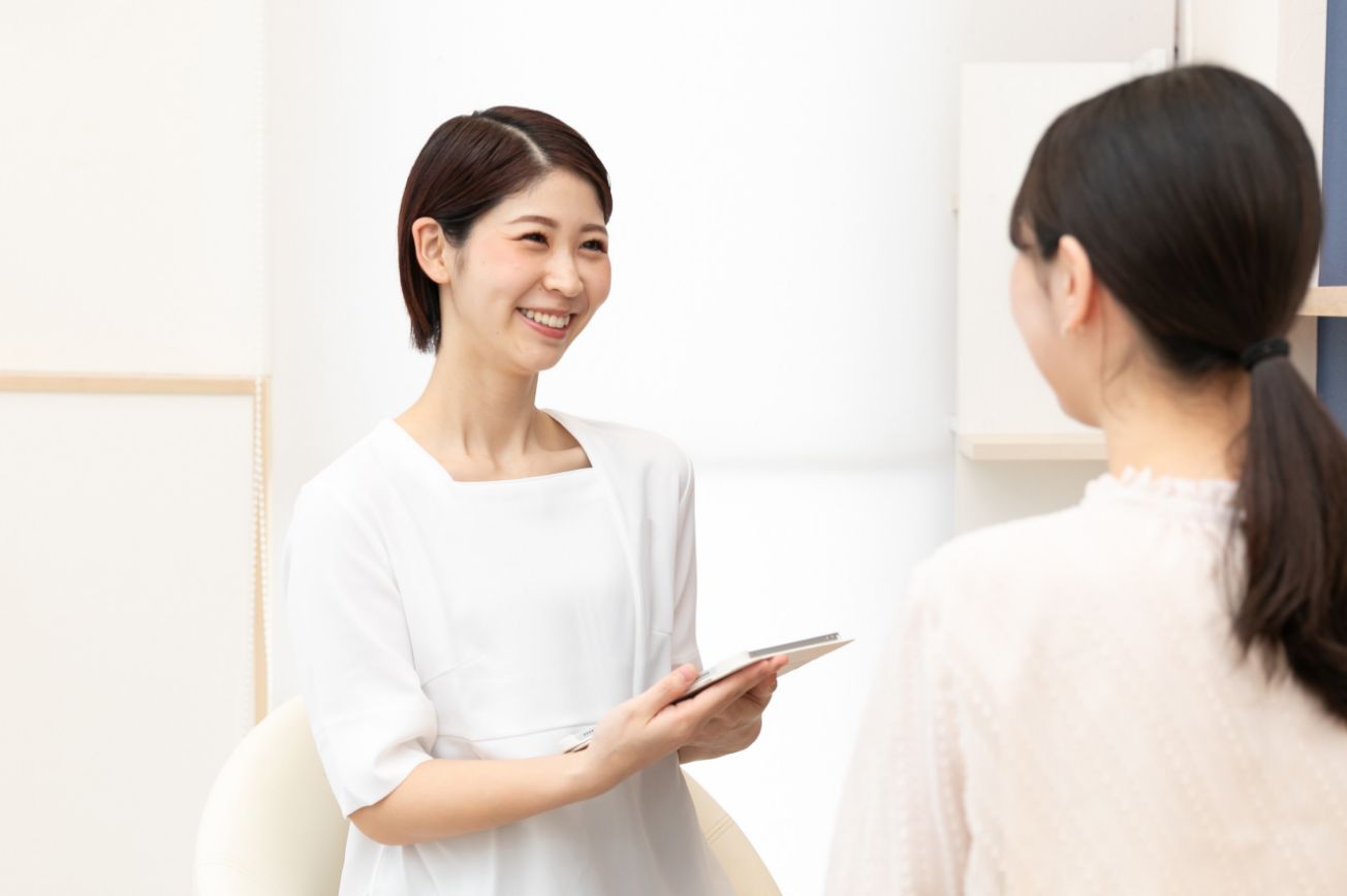 アイパッドを持って笑顔でお客様にご提案する山村さんの画像