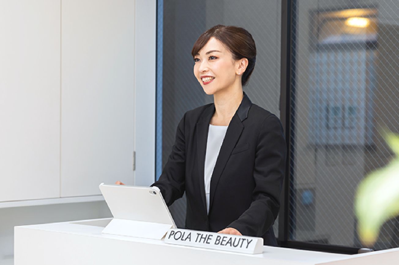 受付に立ってアイパッドを触っている水戸さんの画像